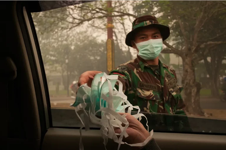 Lampoon, An army officer helps to distribute masks to car passengers driving through the city of Palangkaraya, Central Kalimantan,Aulia Erlangga CIFOR