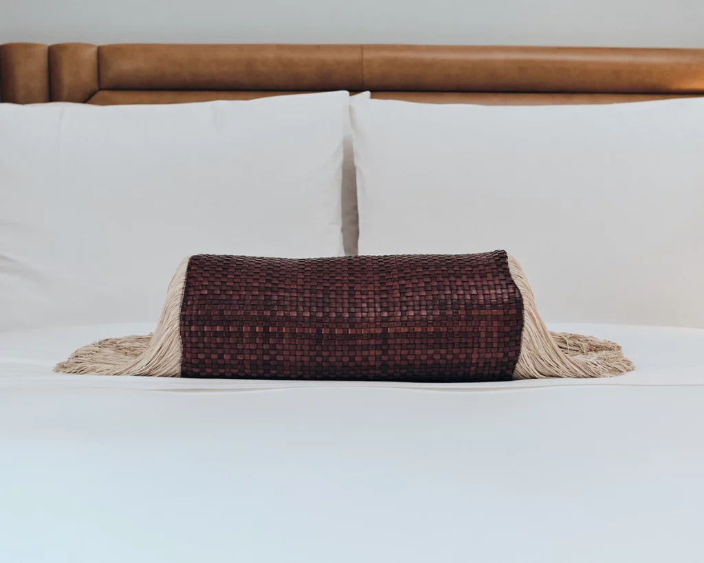 A woven accent pillow adds a touch of texture to the plush bed at W Rome
