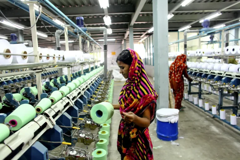 Lampoon A female textile worker works on a machine which dispenses green yarn for use in the production of garments