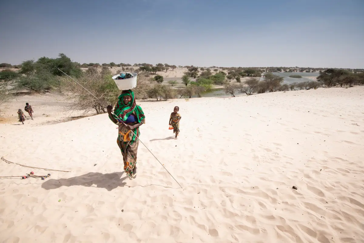 Lampoon, A woman and her child walk on the sand shores that surround Lake Chad, Simon Townsley Panos Pictures