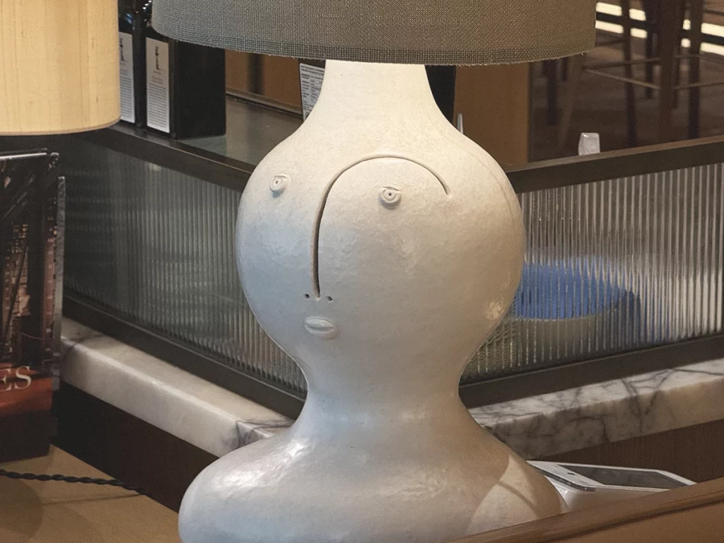 Brach Paris, reception lamp – A playful ceramic base sketched with a smile delivers Starck’s “democratic fun” the moment guests step inside.