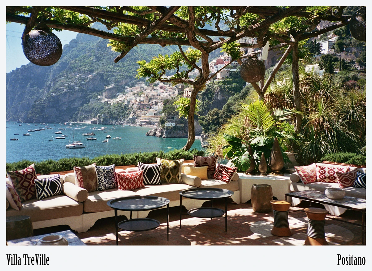 Open-air salon on a cliff-edge terrace_ wrought-iron sofas, hand-woven linen cushions, and the Tyrrhenian Sea—Villa Treville