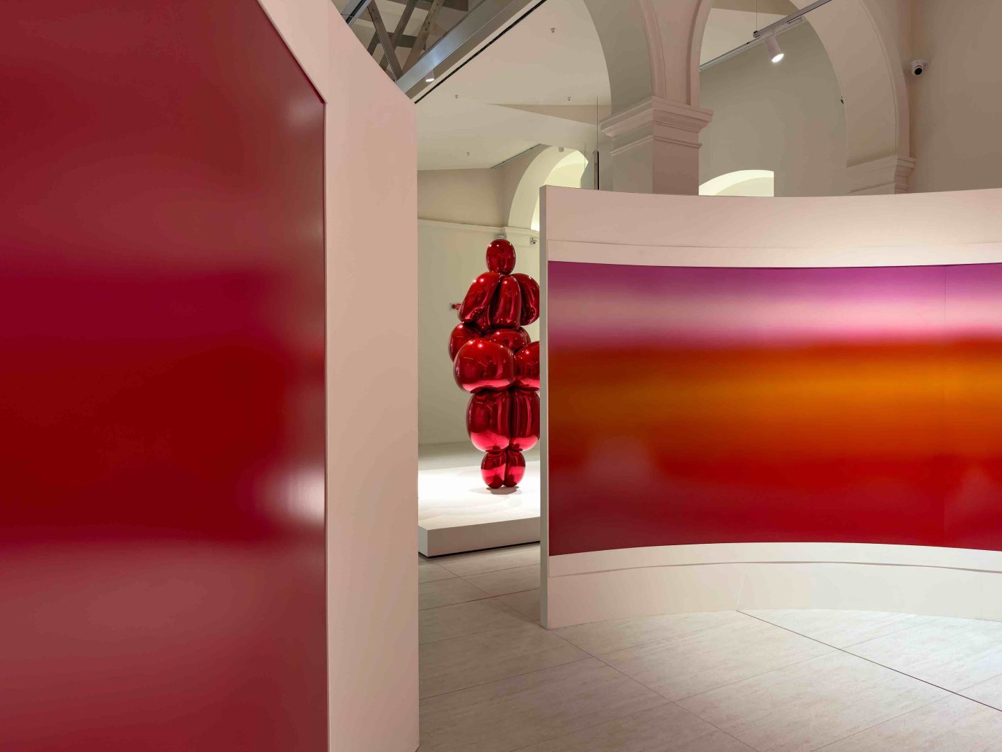Il luminogramma Grand Horizon Panoramique °#1 (2025) di Thomas Paquet si apre su Balloon Venus Lespugue (Red) di Jeff Koons, in un dialogo tra arte contemporanea e riferimenti classici.Orizzonti Rosso, PM23 Roma