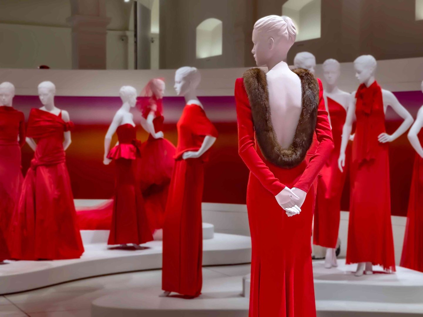 Manichini disposti su pedane circolari, ciascuno vestito in rosso Valentino: un “esercito couture” che marcia verso un futuro di bellezza.Orizzonti Rosso, PM23 Roma