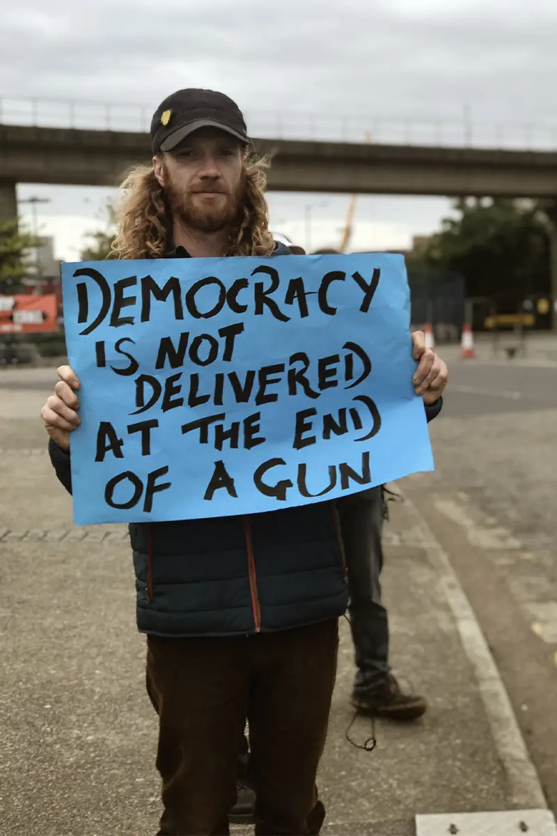 Lampoon, Protestor holds up a sign outside the DSEI site, Credit: Rainbow Collective