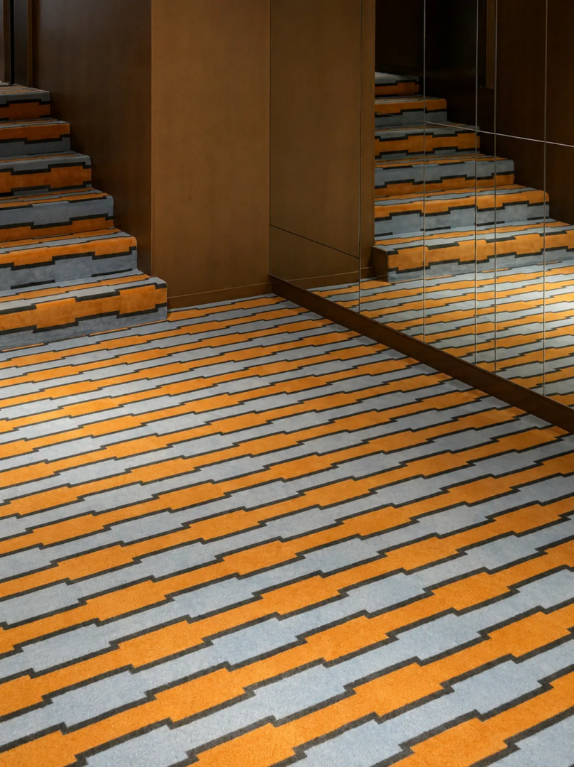 Mirrors multiply the geometry of the interiors, with a patterned carpet marking the transition between levels