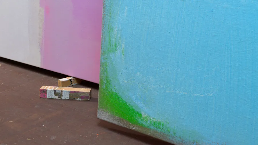 olorful abstract paintings leaning against a studio wall.
