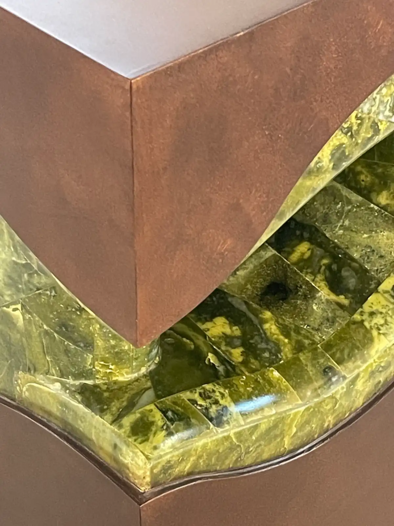 Studio Lél Pakistan object combining oxidized metal and polished green serpentine stone, shown in close-up to highlight the contrasting materials and craftsmanship