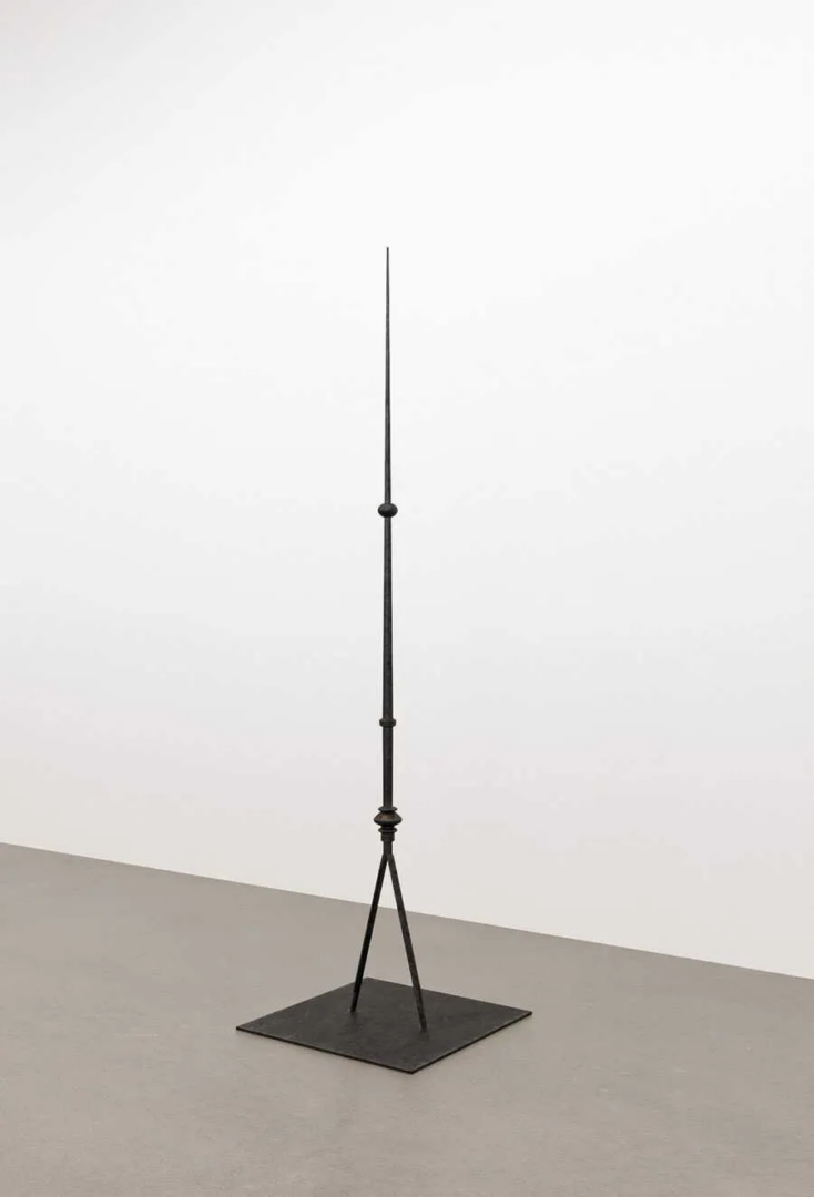 Boz Deseo Garden, Celia, or the Misfortunes of Virtue, 2026. Tall black metal sculpture with a pointed vertical rod, spherical detail and tripod support on a square base.