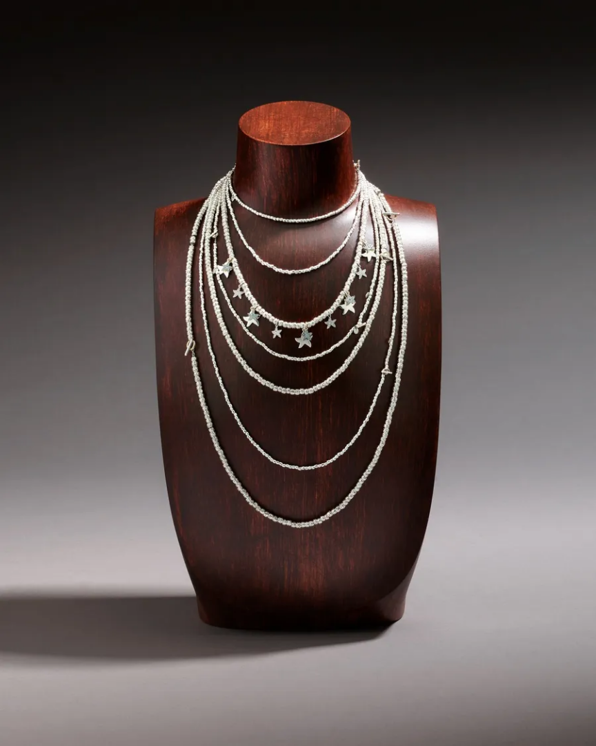 DoDo layered silver-tone beaded necklaces with multiple draped chains and dangling star charms, displayed on a dark wooden bust.