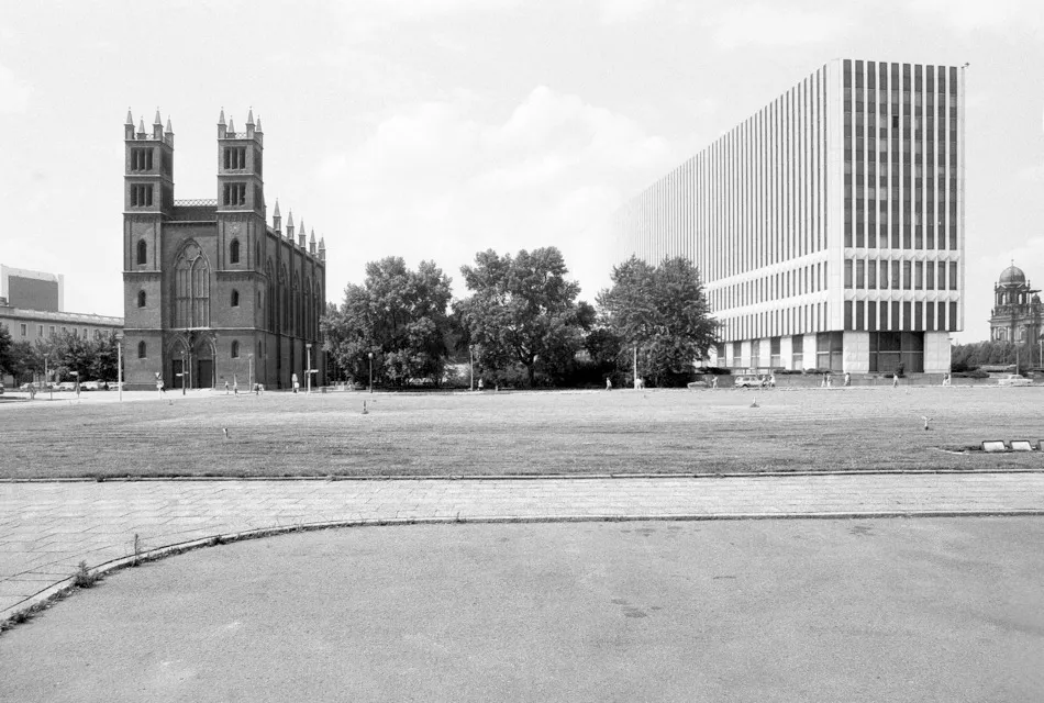 Black-and-white photograph of the GDR Ministry of Foreign Affairs beside Friedrichswerder Church in Berlin, showing the contrast between modernist architecture and historic brick construction.