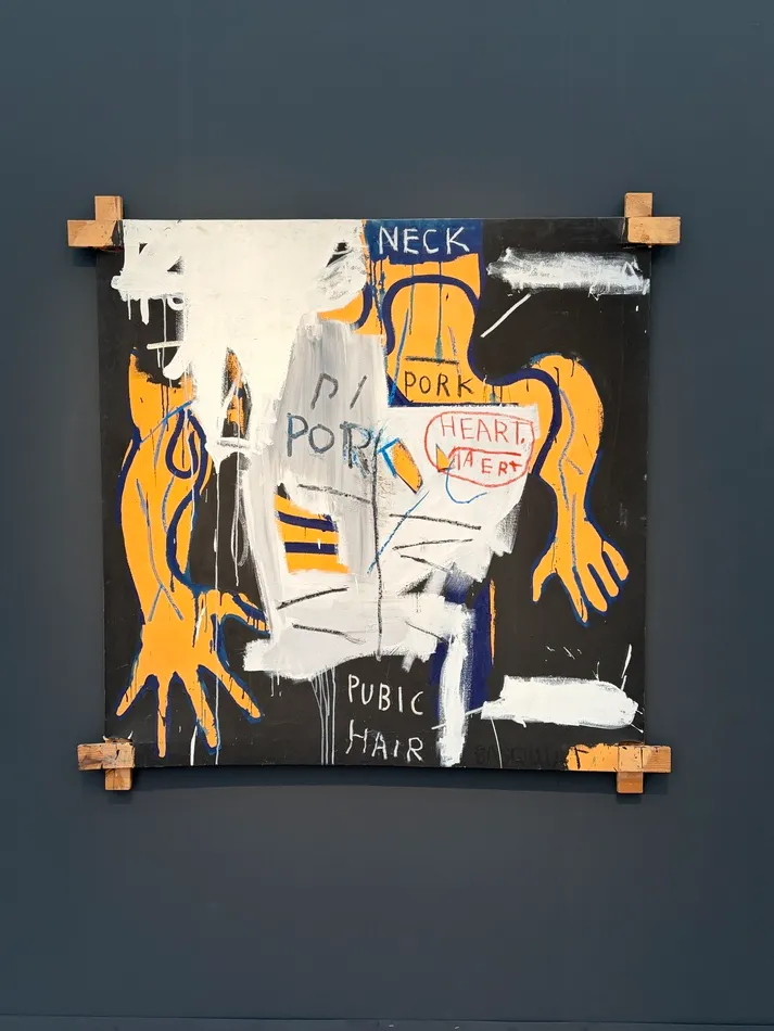 Mixed-media painting by Jean-Michel Basquiat featuring fragmented orange anatomical forms, blue outlines, white brushstrokes and handwritten words including PORK and PUBIC HAIR.