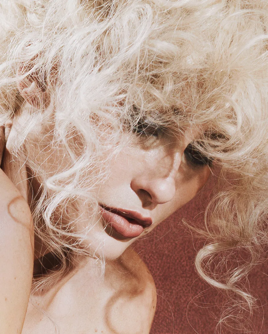 Close-up portrait of Maja Malou Lyse with voluminous platinum-blonde curls, smoky eye makeup and soft pink lips, photographed by Lalo + Eva