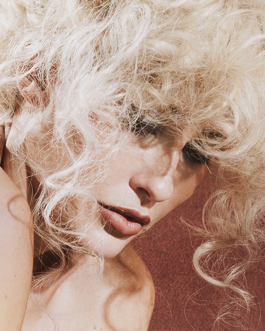 Close-up portrait of Maja Malou Lyse with voluminous platinum-blonde curls, smoky eye makeup and soft pink lips, photographed by Lalo + Eva