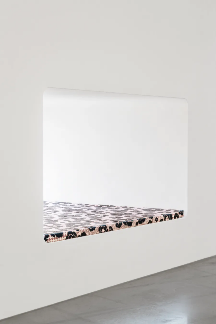 Wall-mounted sculptural work by Lorenza Longhi featuring a white rectangular surface and a projecting shelf covered in black and pink patterned fabric at Centro Pecci.