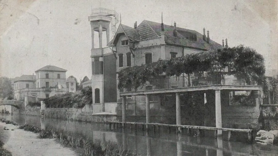 Historical black-and-white photograph of Villa Angelica in Gorla, showing its tower, waterfront terrace and architectural structures along the canal.