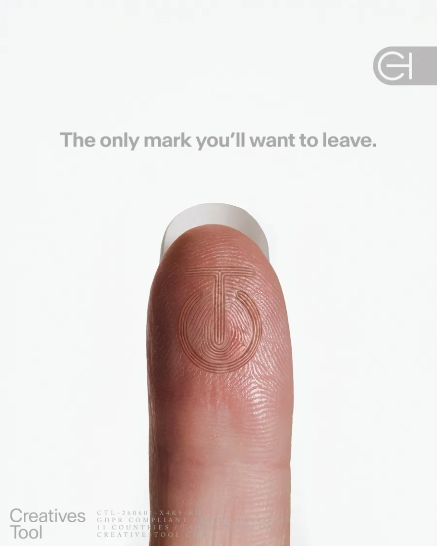 Close-up of a fingertip with an embossed circular logo integrated into the fingerprint, against a white background. Natacha Voranger for Creatives Tool.