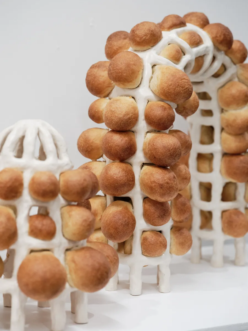 Installation of round bread rolls attached to a white lattice structure forming arches and columns.