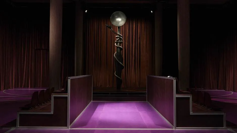 Miu Miu installation with a framed artwork against brown curtains and purple flooring.