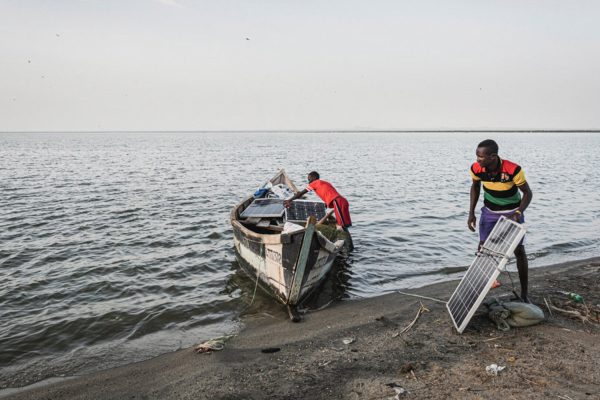 01 05 longech village, two men load solar panels onto a small boat at lake turkana Maurizio Di Pietro, Climate Visuals Countdown
